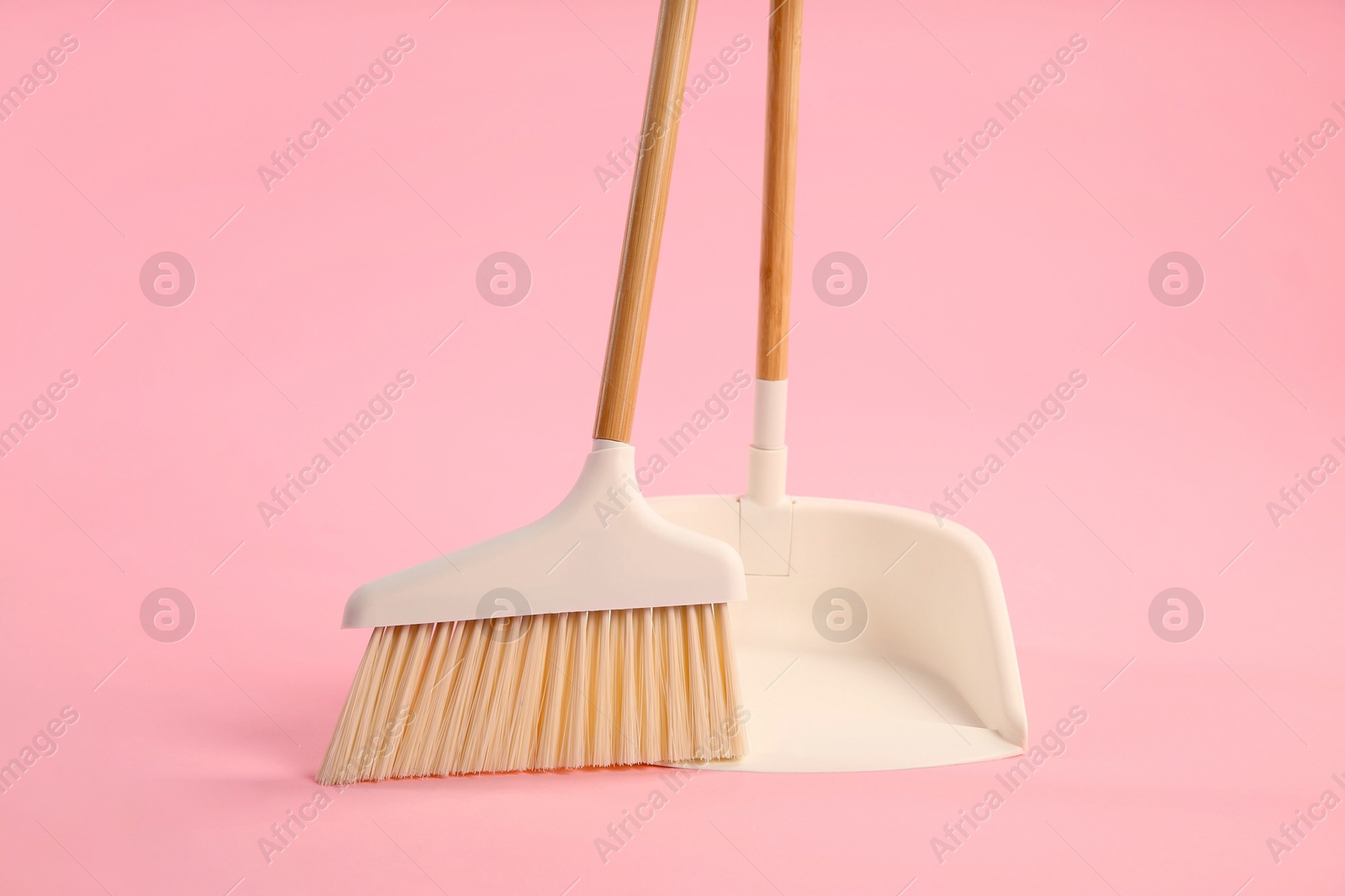 Photo of Cleaning broom and dustpan on pink background