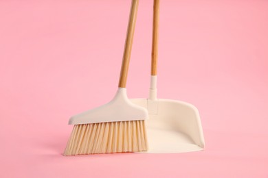 Photo of Cleaning broom and dustpan on pink background