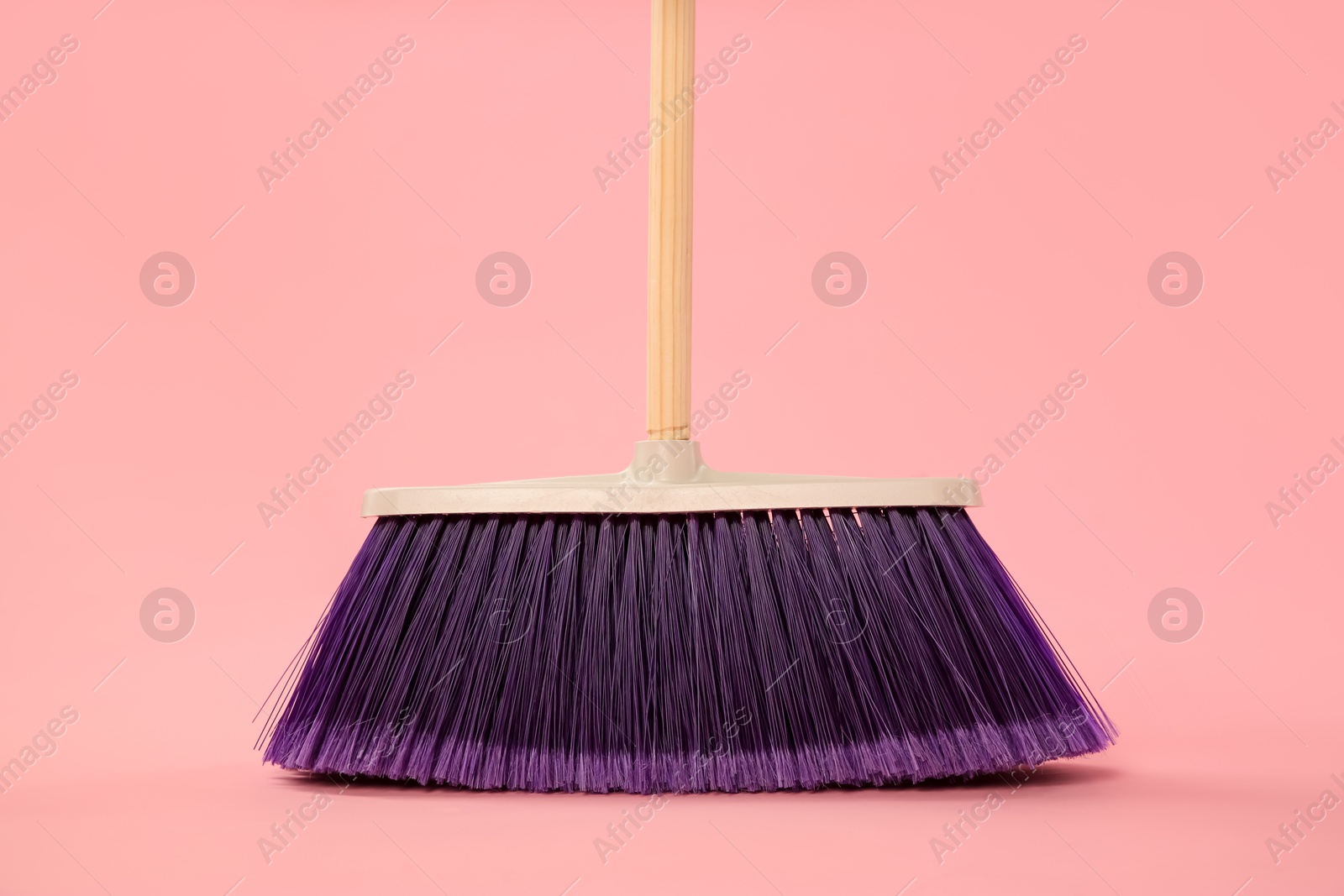 Photo of One bright cleaning broom on pink background