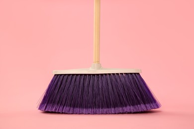 Photo of One bright cleaning broom on pink background