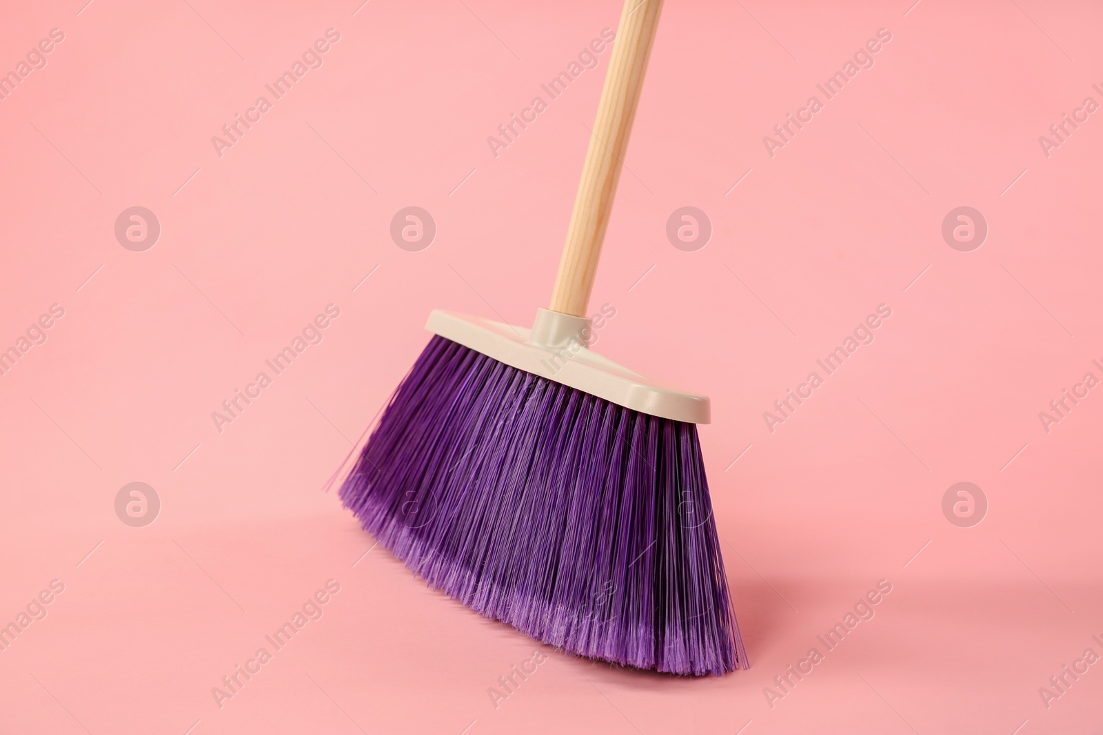 Photo of One bright cleaning broom on pink background