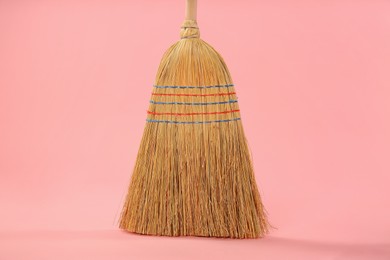 Photo of One corn straw broom on pink background