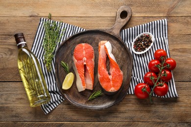 Photo of Fresh salmon steaks, peppercorns, oil and products on wooden table, top view