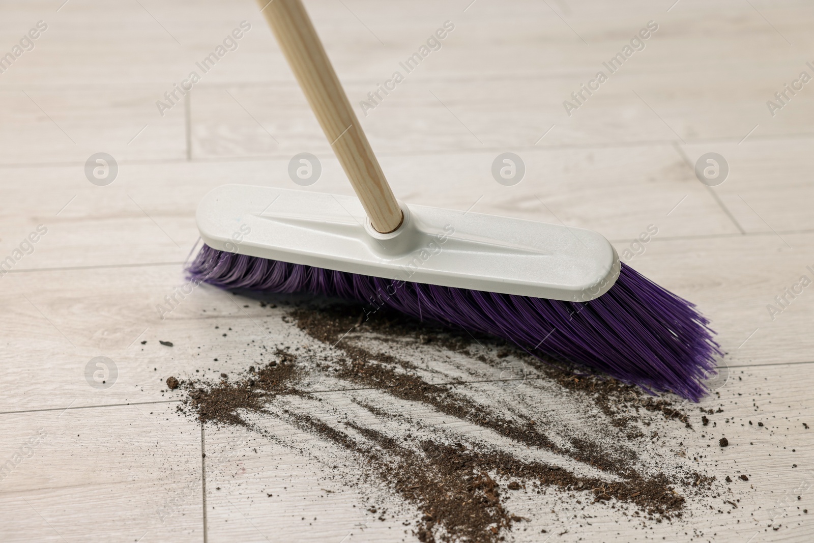 Photo of Sweeping wooden floor with bright broom indoors