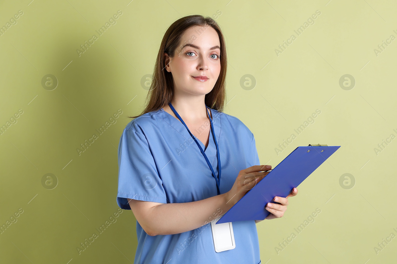 Photo of Professional nurse with clipboard on pale green background