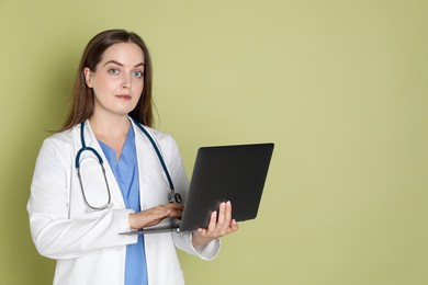 Professional nurse working with laptop on pale green background. Space for text