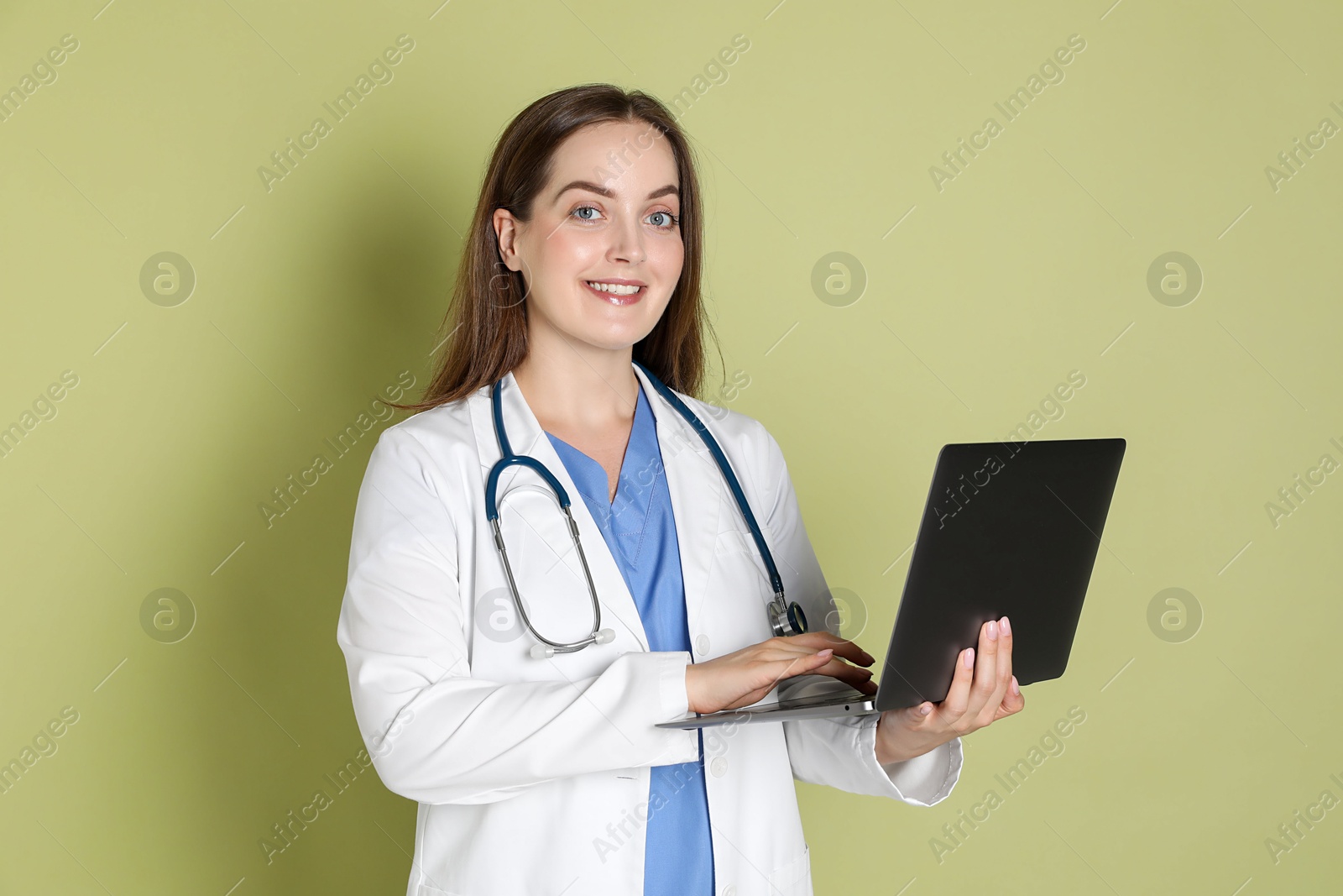 Photo of Professional nurse working with laptop on pale green background