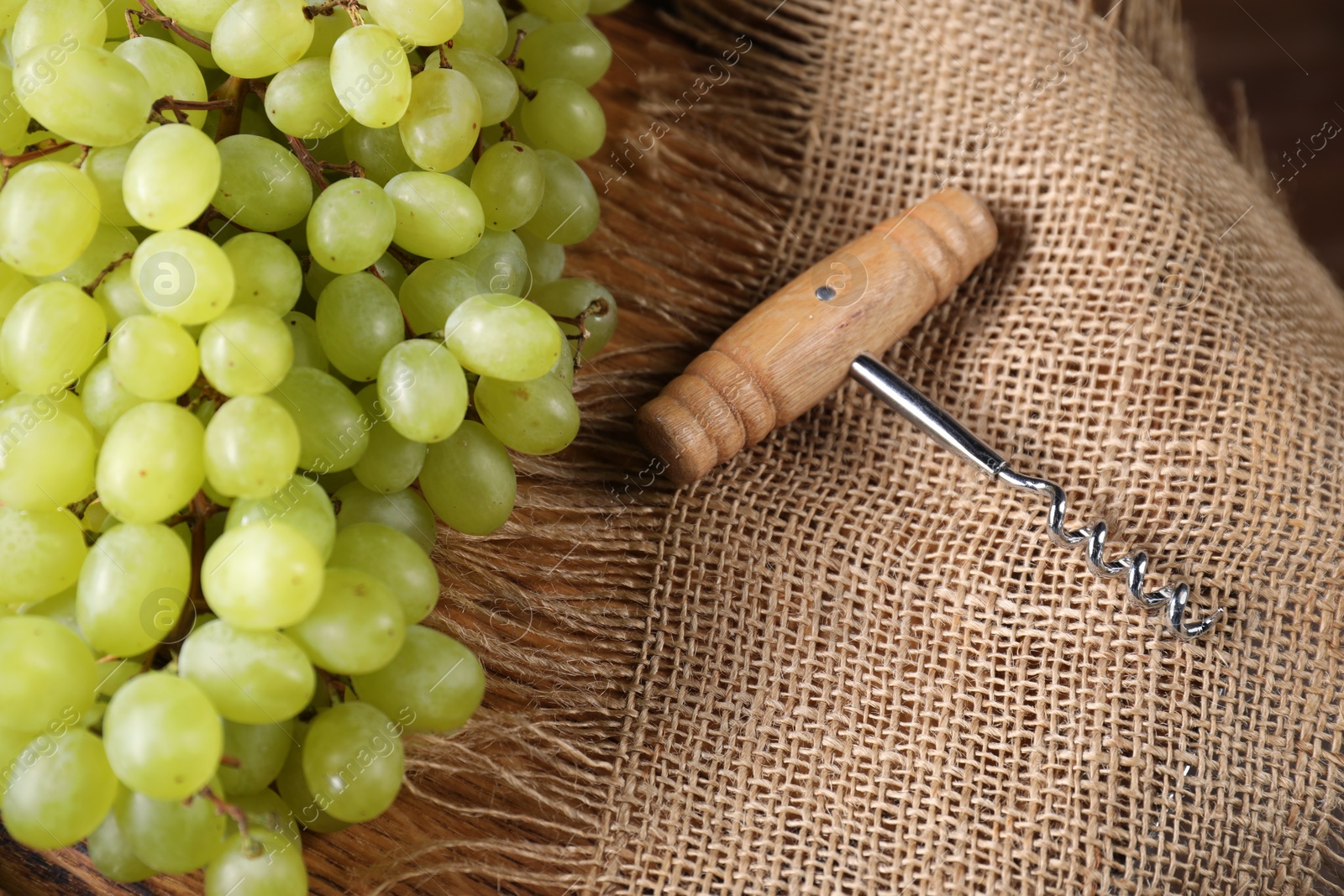 Photo of Corkscrew and grapes on burlap fabric, closeup