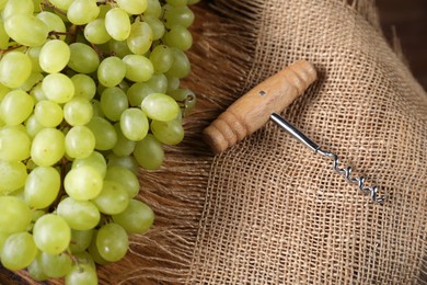 Corkscrew and grapes on burlap fabric, closeup