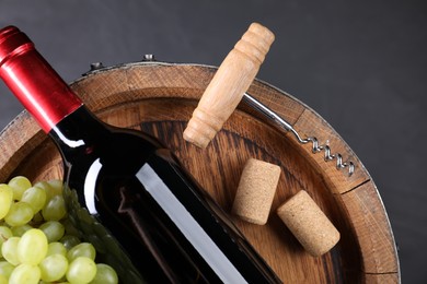 Photo of Corkscrew, bottle of wine, grapes, corks and wooden barrel on grey table, top view