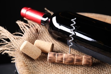 Photo of Corkscrew, bottle of wine and corks on barrel, closeup