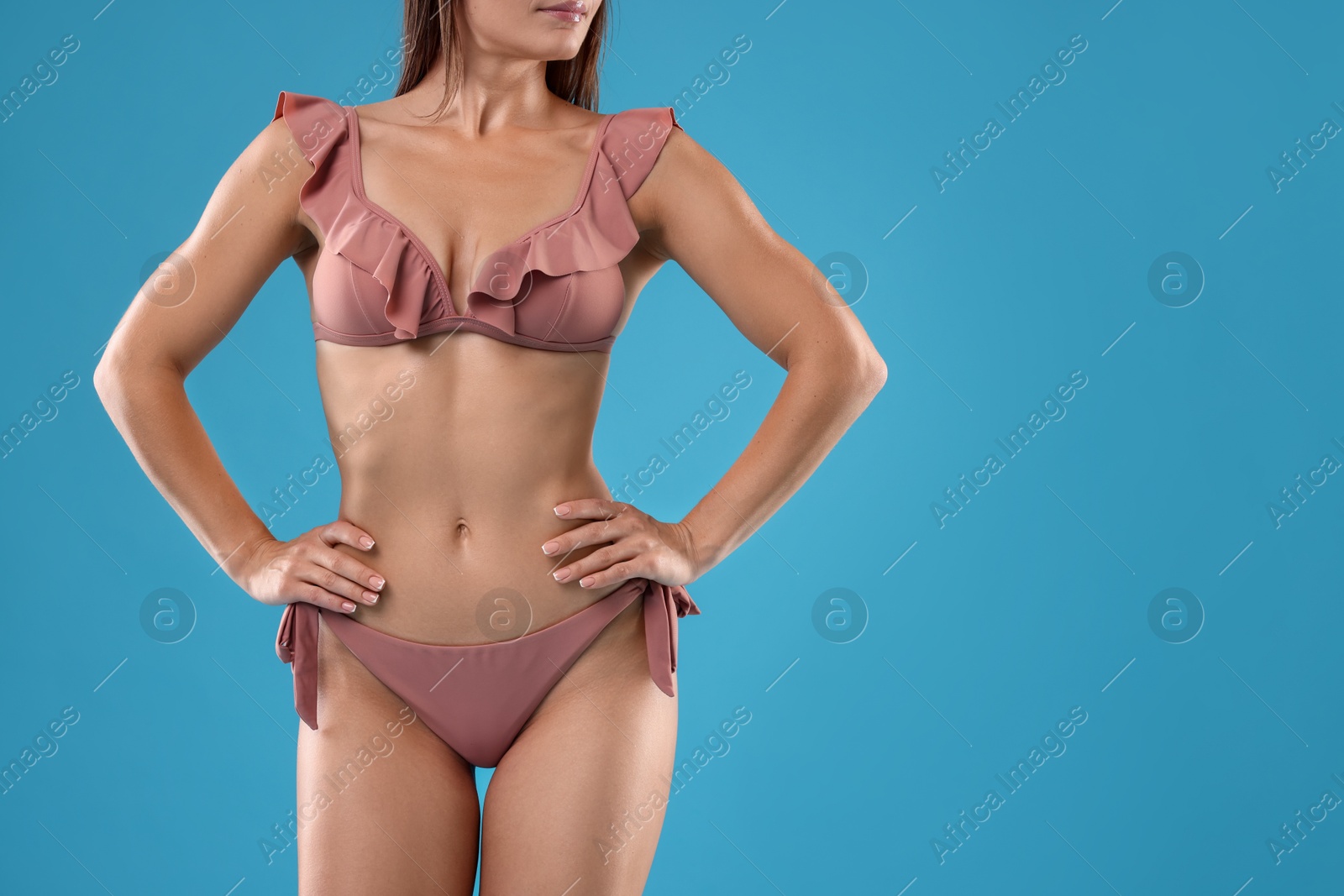 Photo of Woman in bikini on light blue background, closeup. Space for text