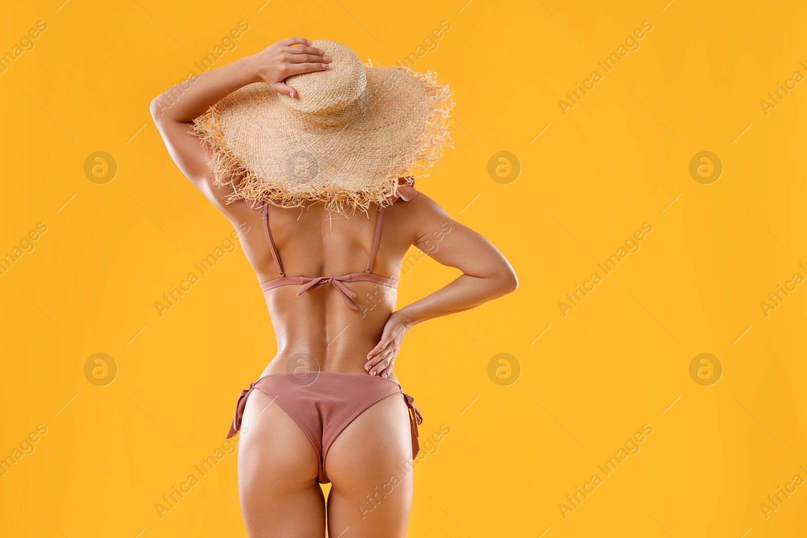 Photo of Woman in stylish bikini on orange background, back view. Space for text