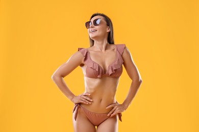 Woman in stylish bikini on orange background