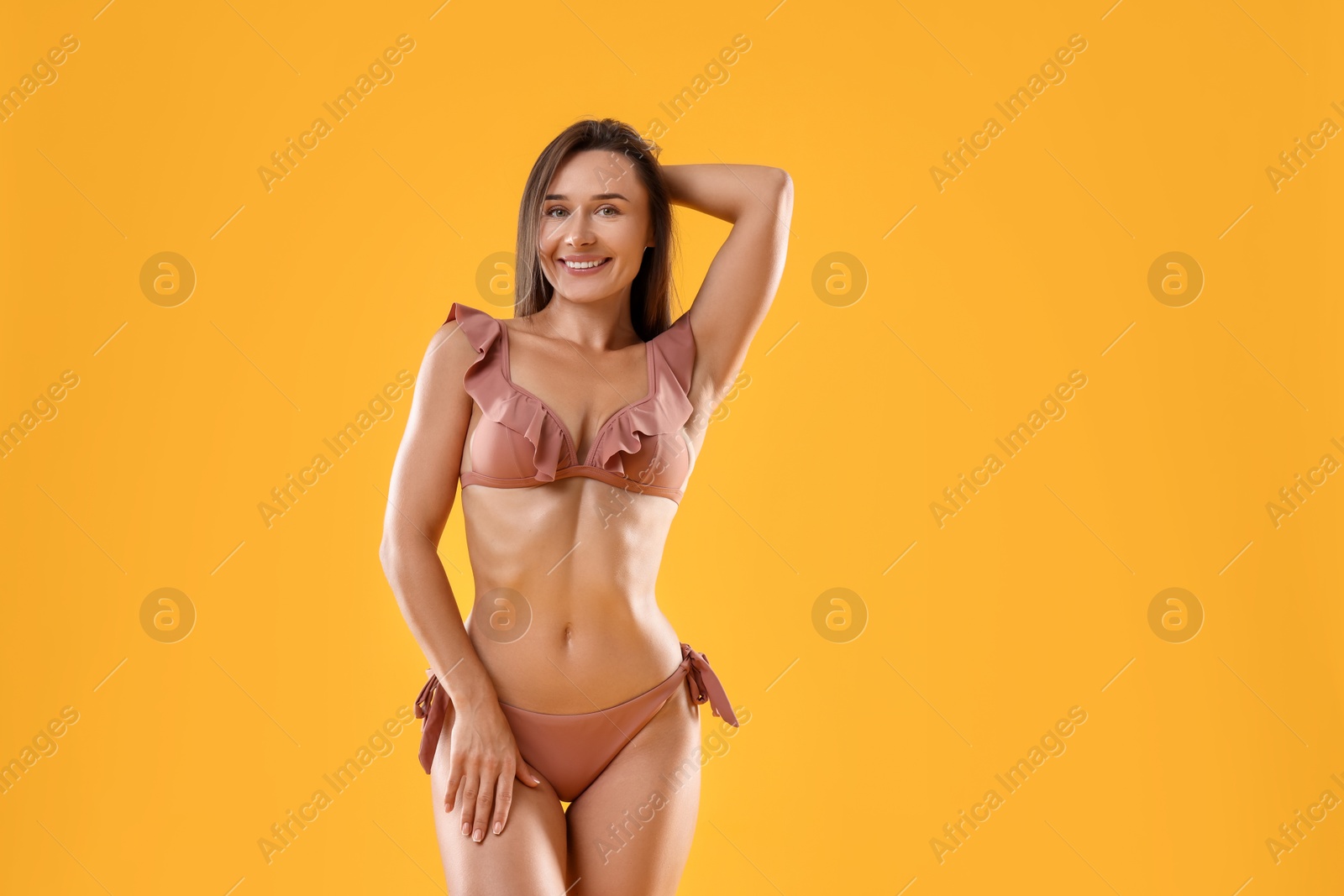 Photo of Woman in stylish bikini on orange background, space for text