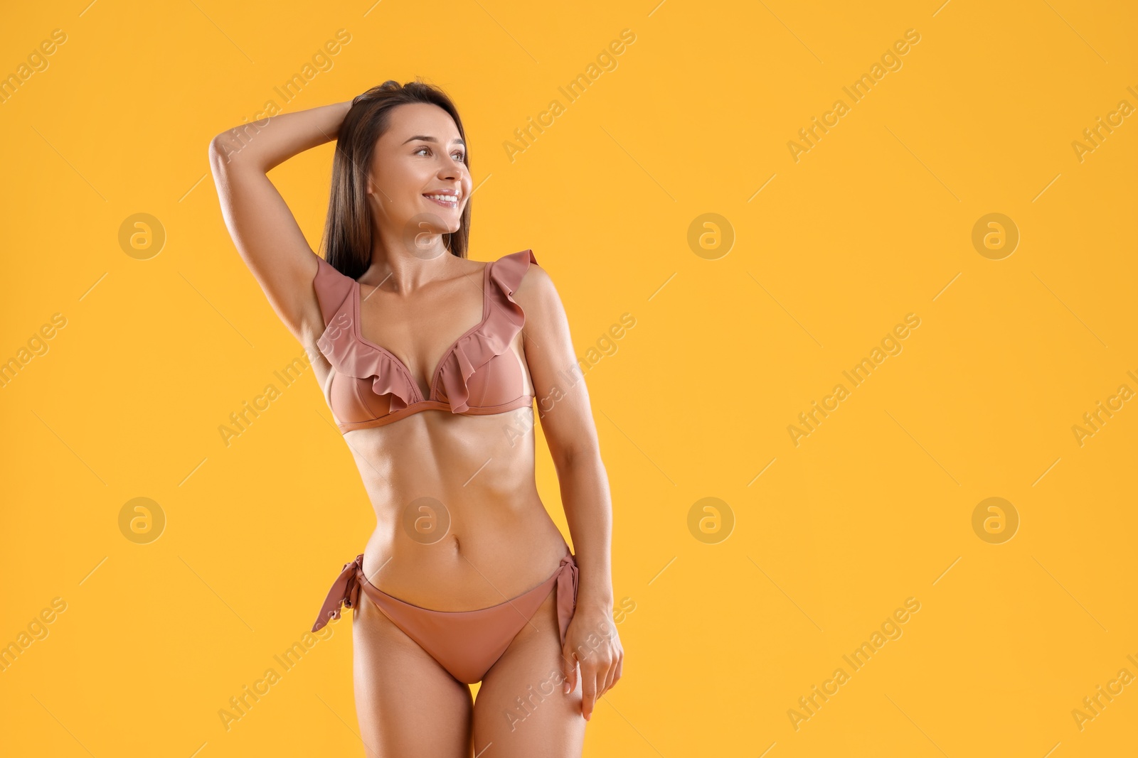 Photo of Woman in stylish bikini on orange background, space for text