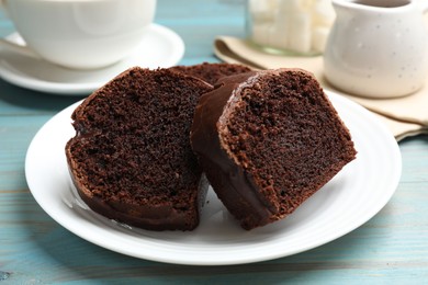 Photo of Slices of tasty chocolate sponge cake on light blue wooden table, closeup