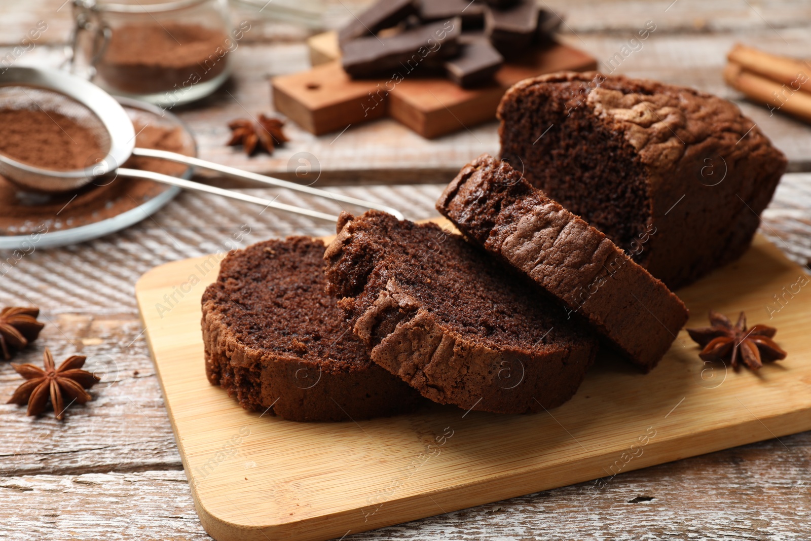 Delicious cut chocolate sponge cake and ingredients on wooden table, closeup Photo of Delicious cut chocolate sponge cake and ingredients on wooden table, closeup