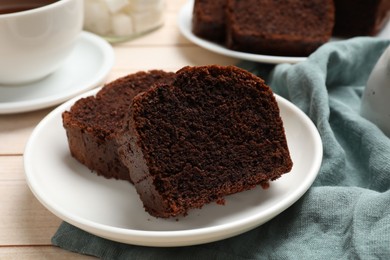 Photo of Slices of delicious chocolate sponge cake on white wooden table, closeup