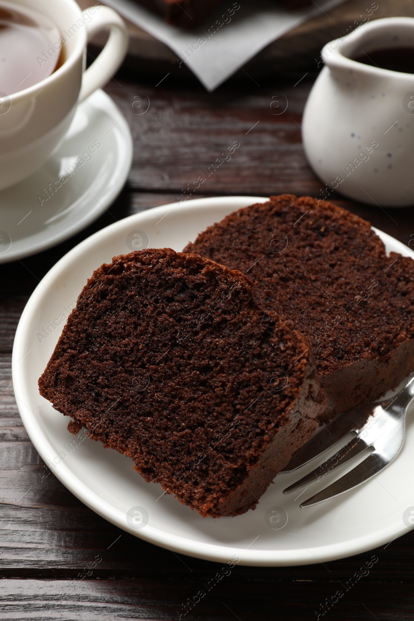 Photo of Slices of delicious chocolate sponge cake on wooden table, closeup