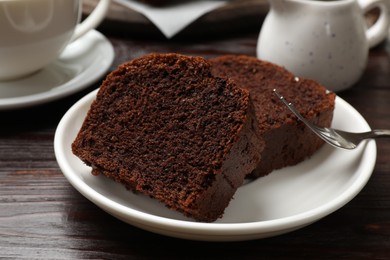 Photo of Slices of delicious chocolate sponge cake on wooden table, closeup