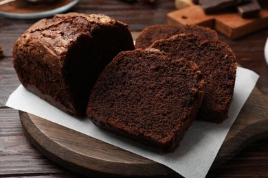 Photo of Delicious cut chocolate sponge cake on wooden table, closeup