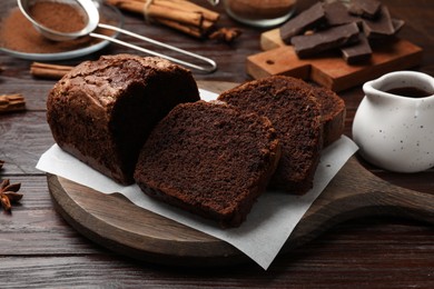 Photo of Delicious cut chocolate sponge cake on wooden table, closeup