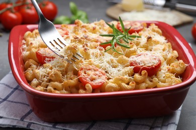 Photo of Eating delicious al forno pasta at grey table, closeup