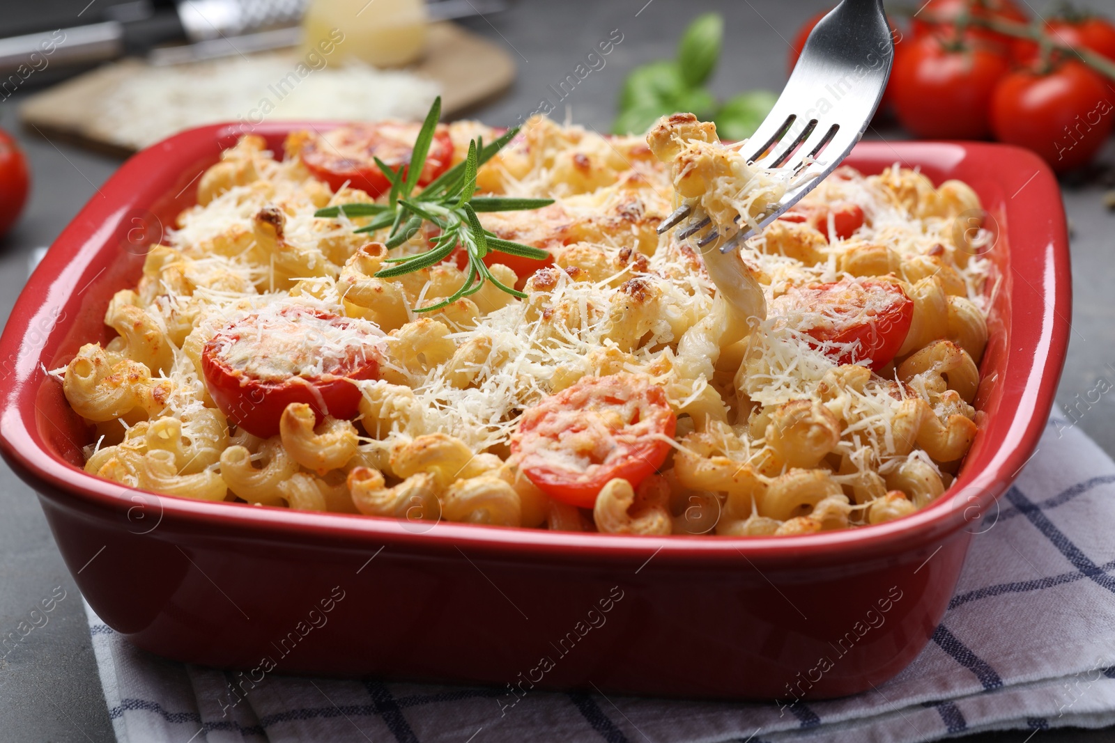 Photo of Eating delicious al forno pasta at grey table, closeup