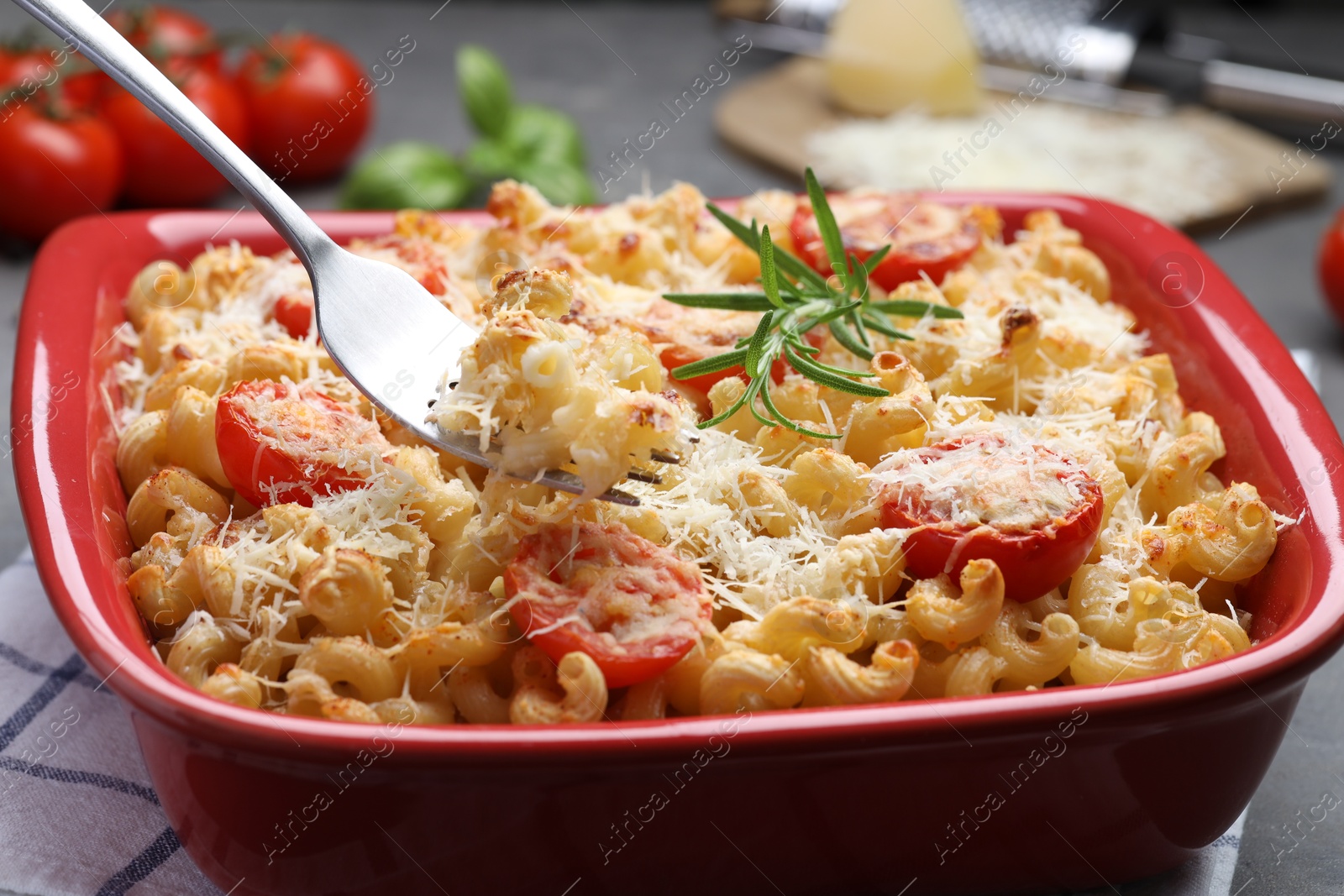 Photo of Eating delicious al forno pasta at grey table, closeup