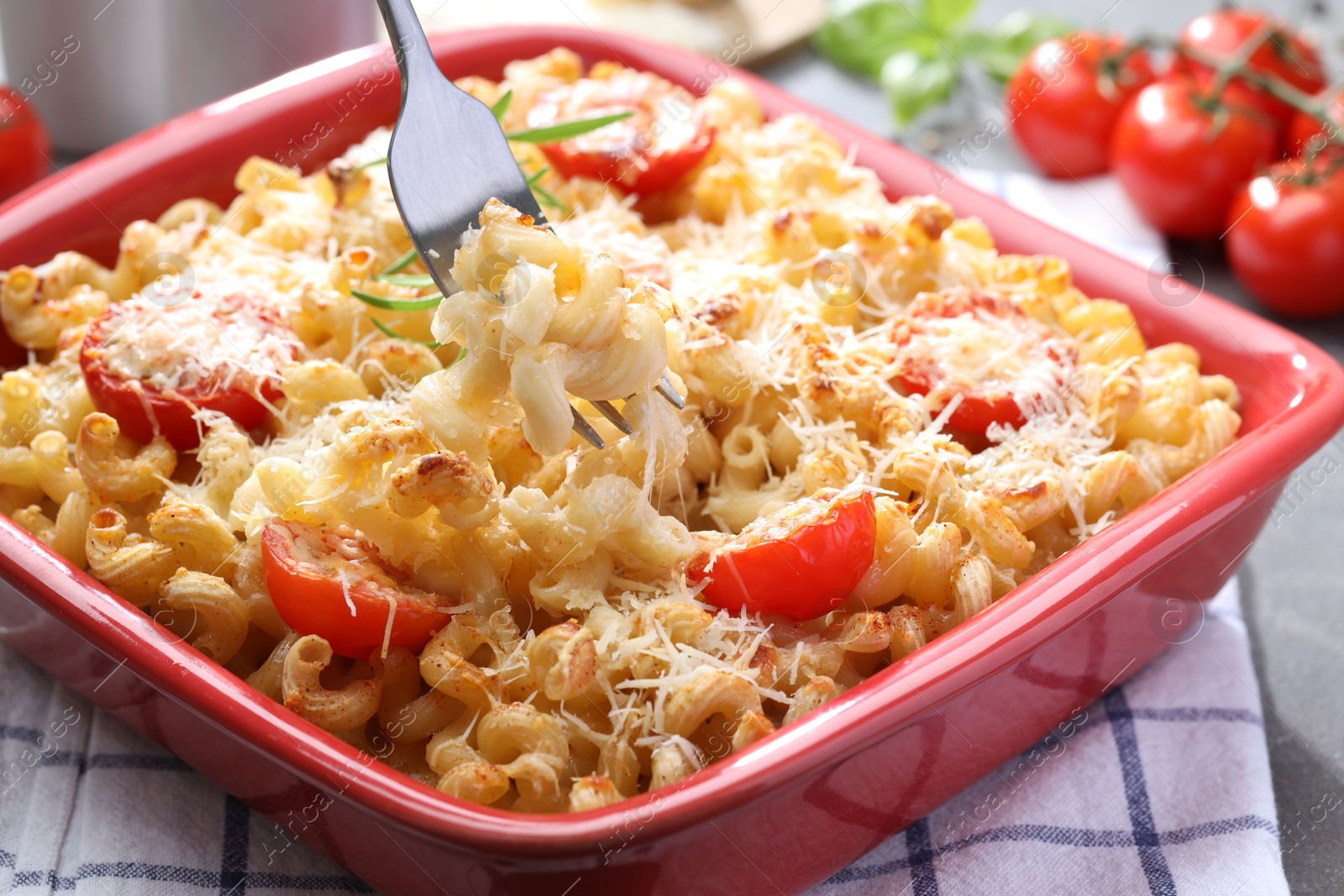 Photo of Eating delicious al forno pasta at grey table, closeup