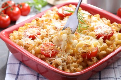 Photo of Eating delicious al forno pasta at grey table, closeup