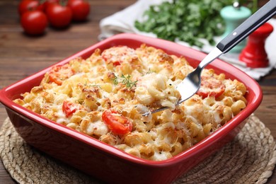 Photo of Eating delicious al forno pasta at wooden table, closeup