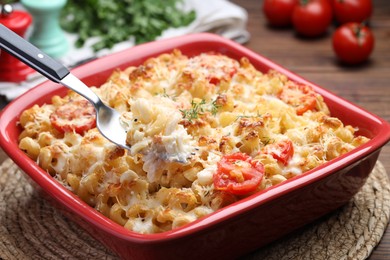 Photo of Eating delicious al forno pasta at wooden table, closeup