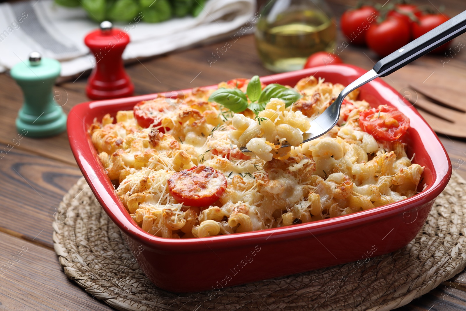 Photo of Eating delicious al forno pasta at wooden table, closeup