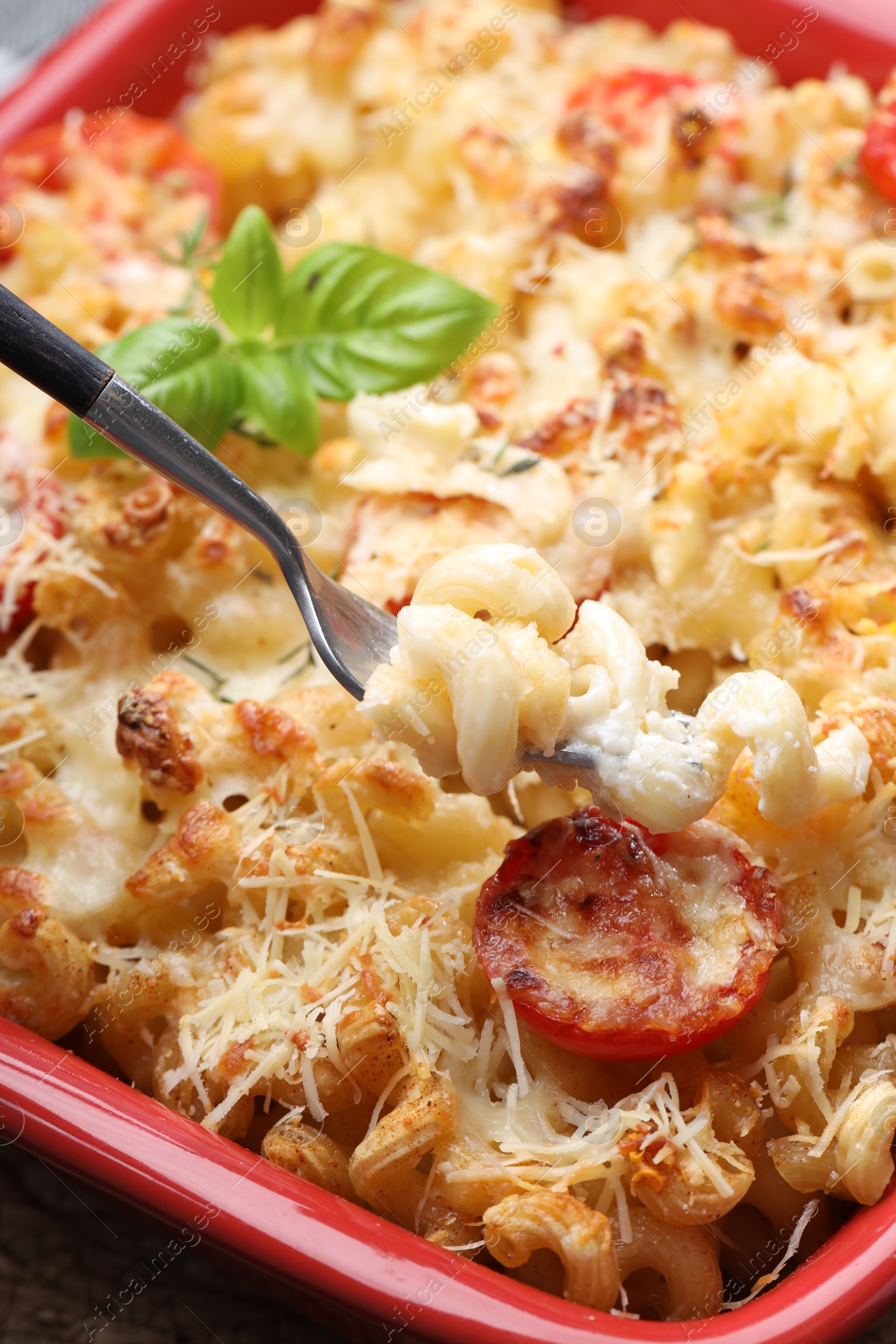 Photo of Eating delicious al forno pasta at table, closeup