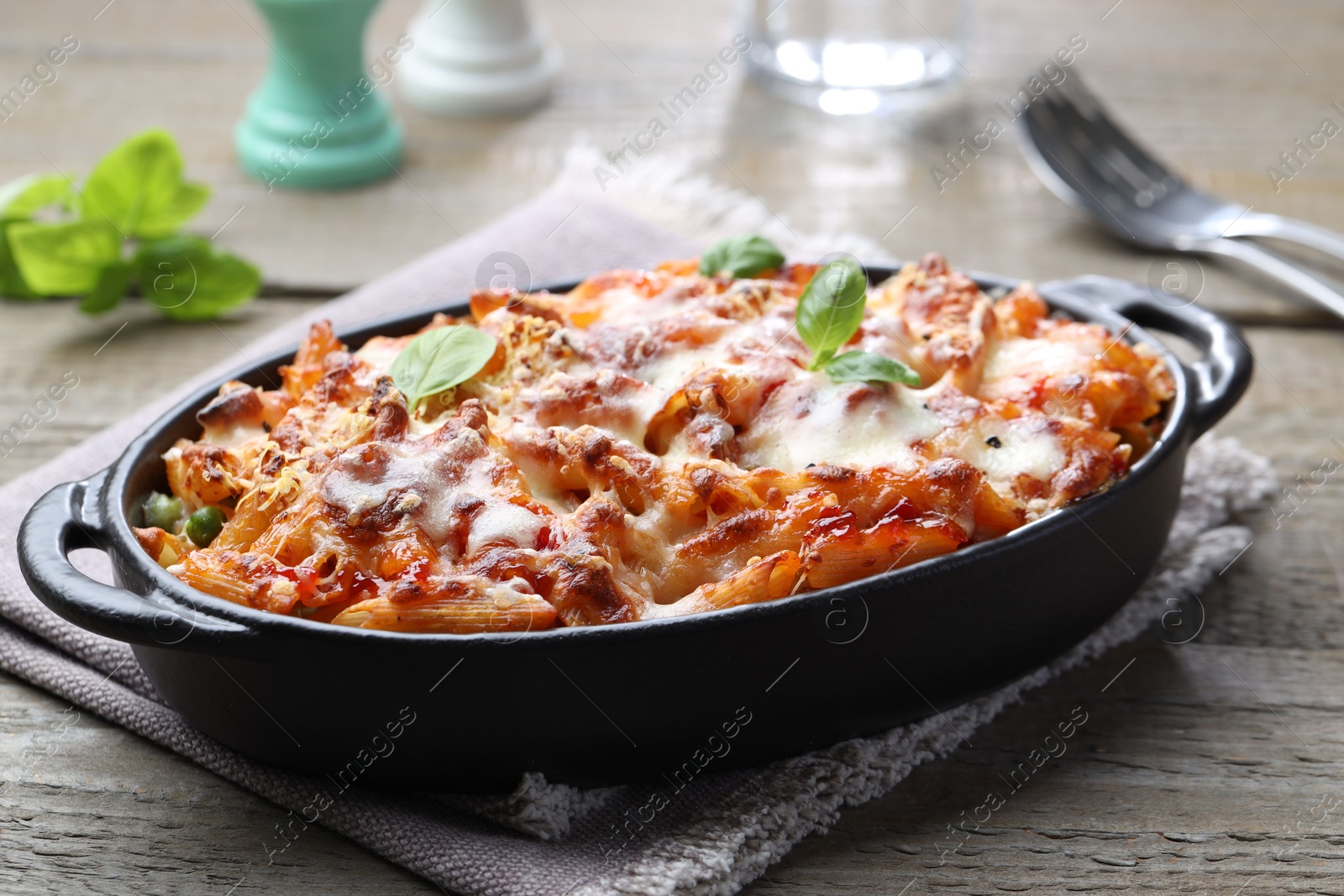 Photo of Delicious al forno pasta in baking dish on wooden table, closeup