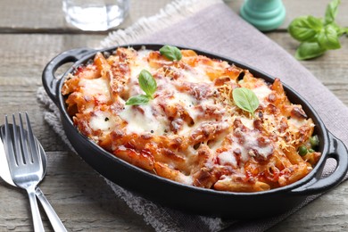 Photo of Delicious al forno pasta in baking dish on wooden table, closeup