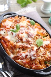 Photo of Delicious al forno pasta in baking dish on wooden table, closeup