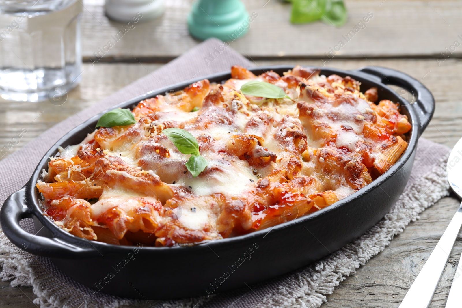 Photo of Delicious al forno pasta in baking dish on wooden table, closeup