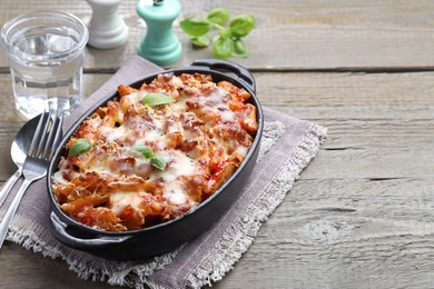 Photo of Delicious al forno pasta in baking dish on wooden table