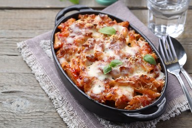 Photo of Delicious al forno pasta in baking dish on wooden table, closeup