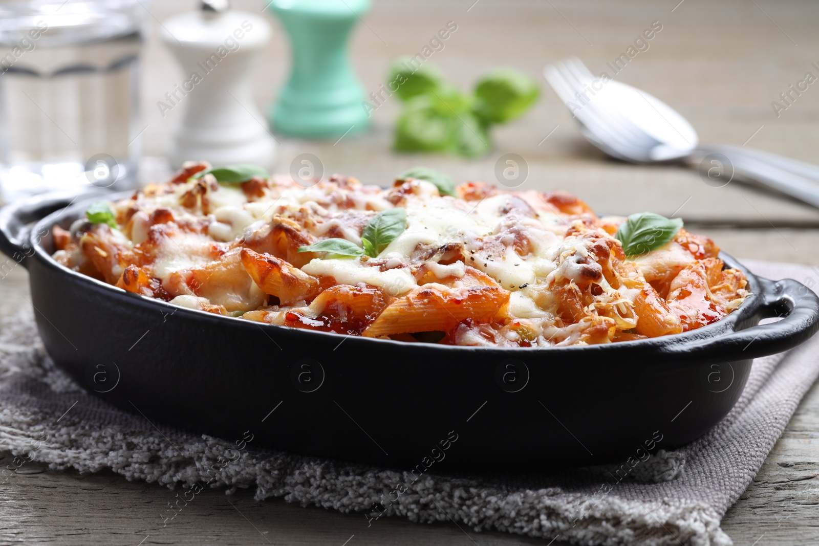 Photo of Delicious al forno pasta in baking dish on wooden table, closeup