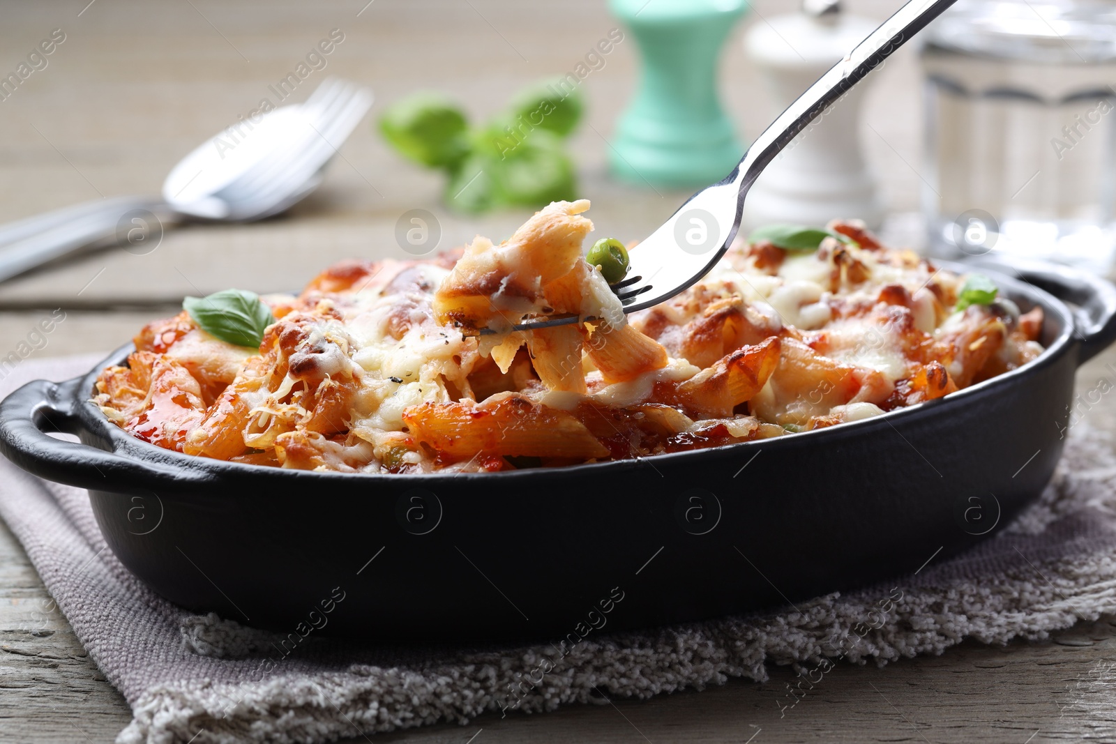 Photo of Eating delicious al forno pasta at wooden table, closeup