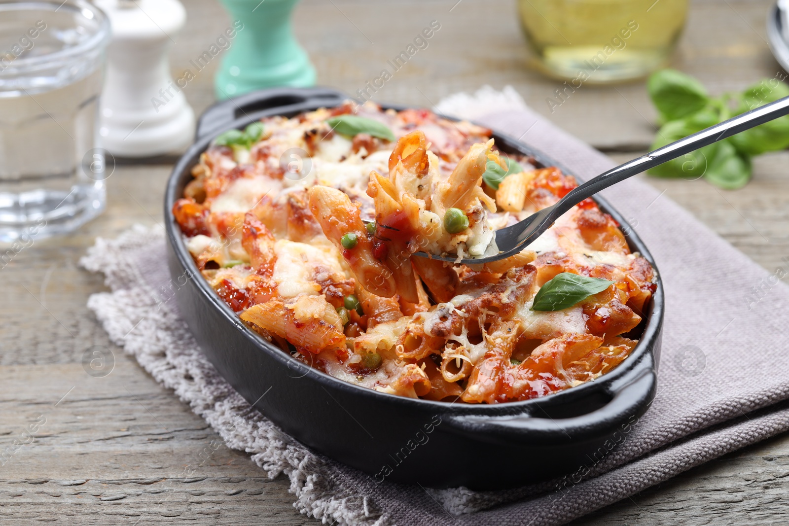 Photo of Eating delicious al forno pasta at wooden table, closeup