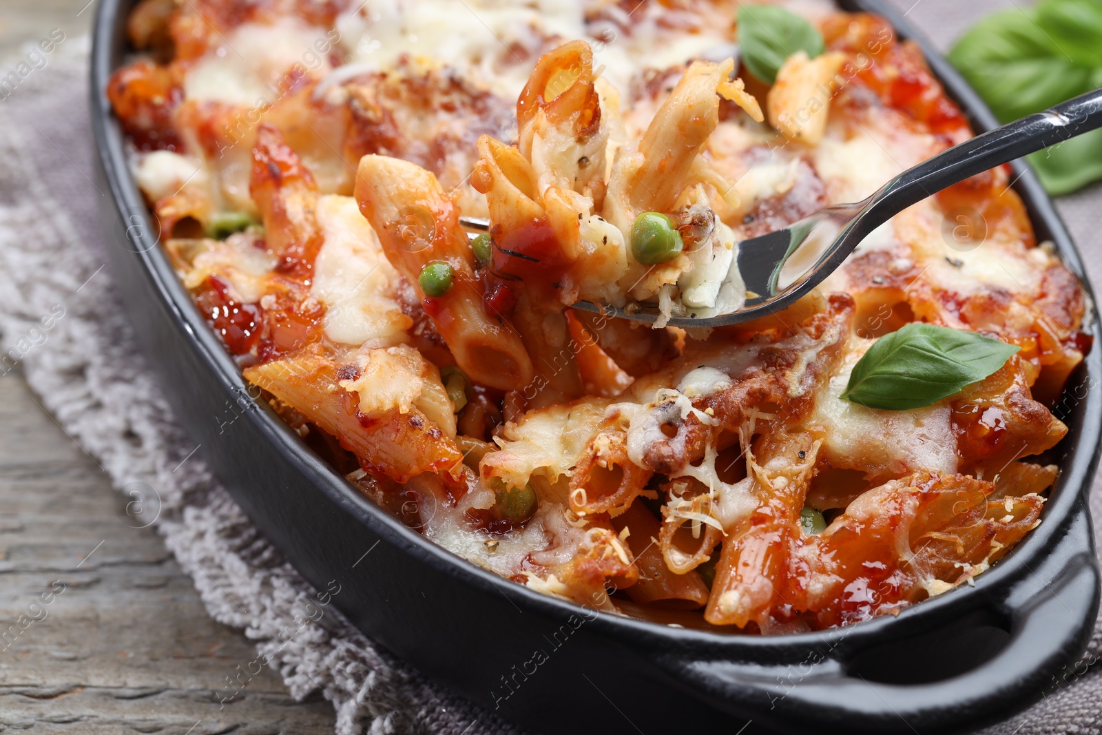 Photo of Eating delicious al forno pasta at wooden table, closeup