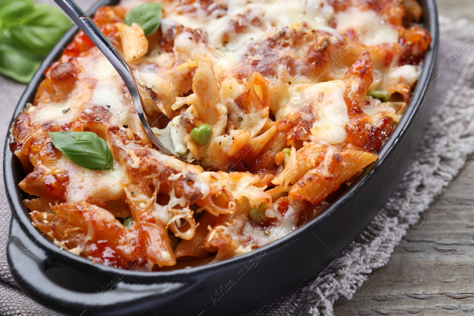 Photo of Eating delicious al forno pasta at wooden table, closeup