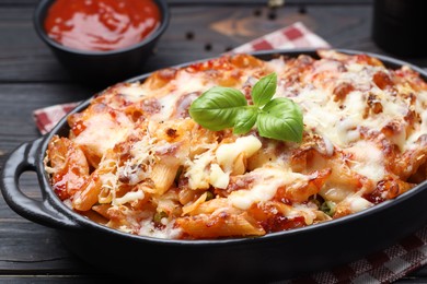 Photo of Delicious al forno pasta in baking dish on wooden table, closeup