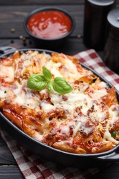 Photo of Delicious al forno pasta in baking dish on wooden table, closeup