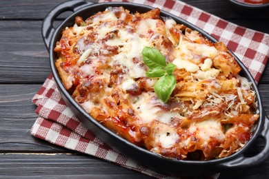 Photo of Delicious al forno pasta in baking dish on wooden table, closeup